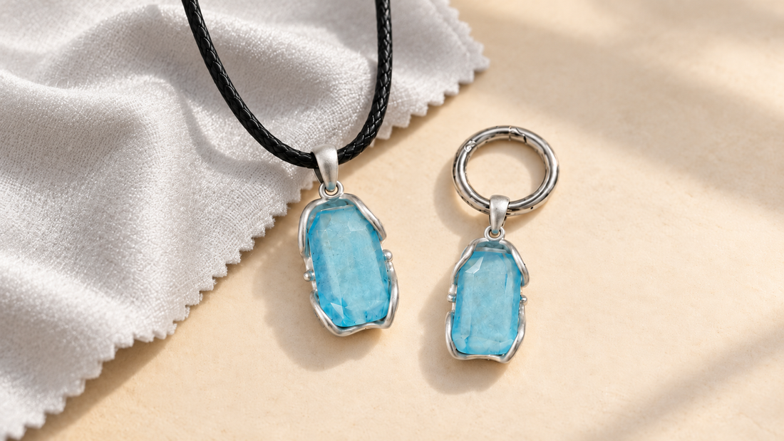 VeilBond aquamarine necklace and matching pet collar charm beside a soft silver polishing cloth on a warm beige background