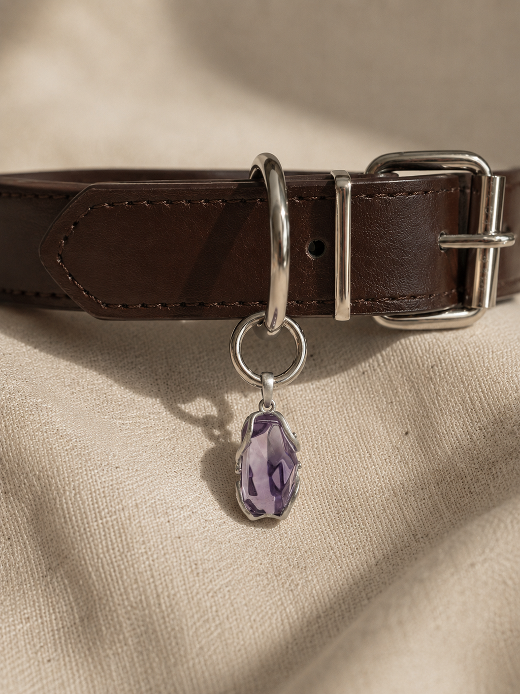 VeilBond Quiet Harbor amethyst pet collar charm in a copper setting, attached to a pet collar and shown in a close-up detail view.