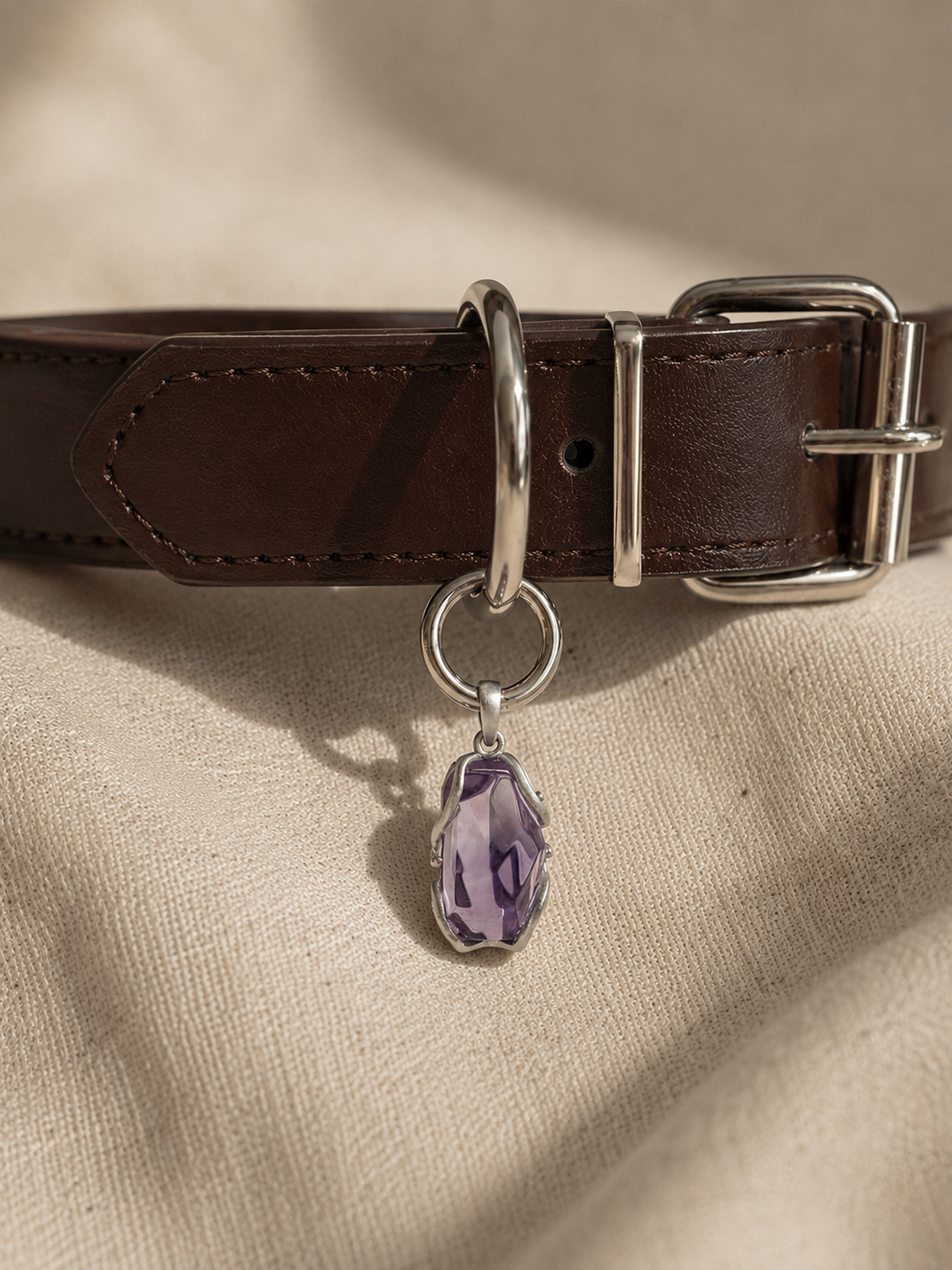 VeilBond Quiet Harbor amethyst pet collar charm in a copper setting, attached to a pet collar and shown in a close-up detail view.
