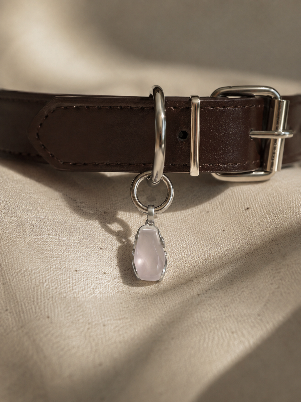 VeilBond Tender Thread rose quartz pet collar charm in a copper setting, attached to a pet collar and shown in a close-up detail view.