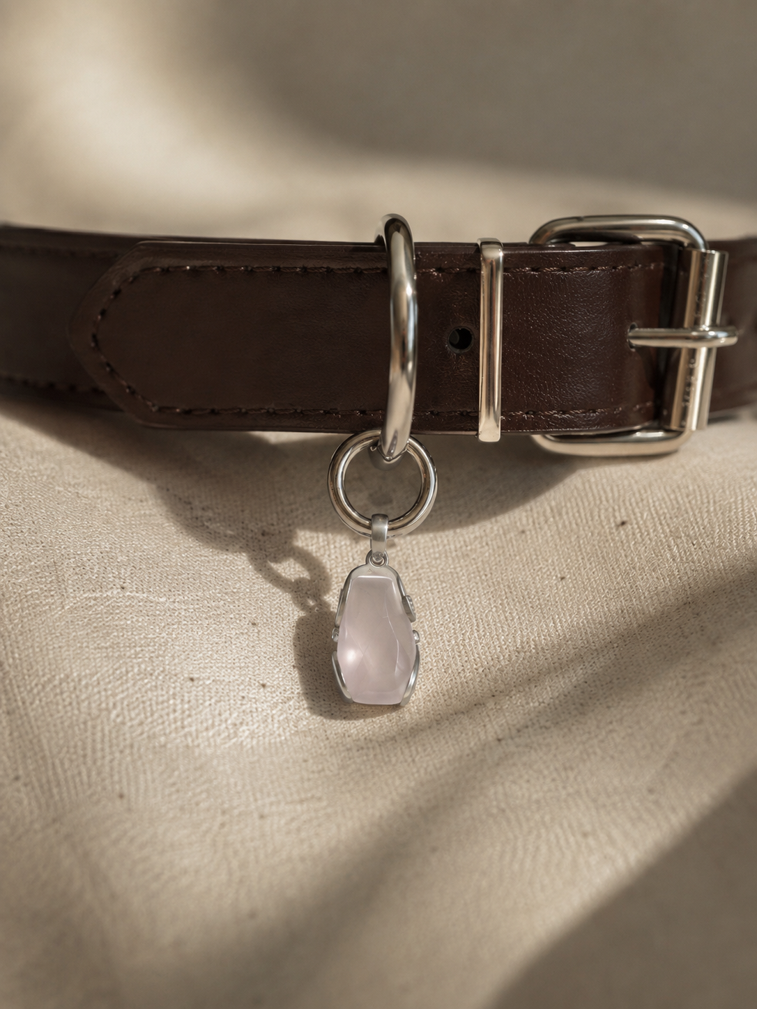 VeilBond Tender Thread rose quartz pet collar charm in a copper setting, attached to a pet collar and shown in a close-up detail view.