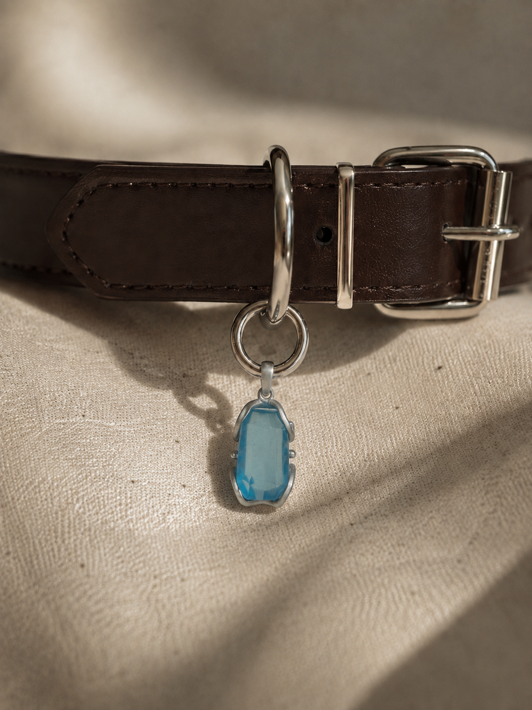 VeilBond Through the Tide aquamarine pet collar charm in a copper setting, attached to a pet collar and shown in a close-up detail view.